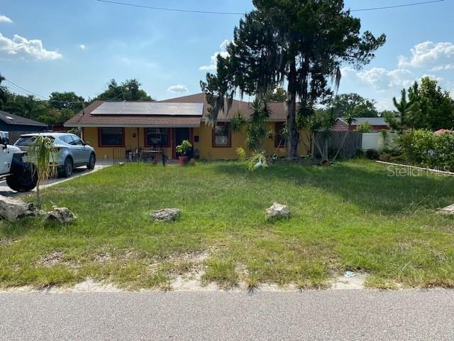 view of front of house with a front yard and solar panels