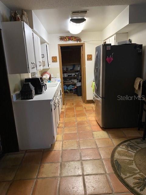 kitchen with light tile patterned floors and stainless steel refrigerator