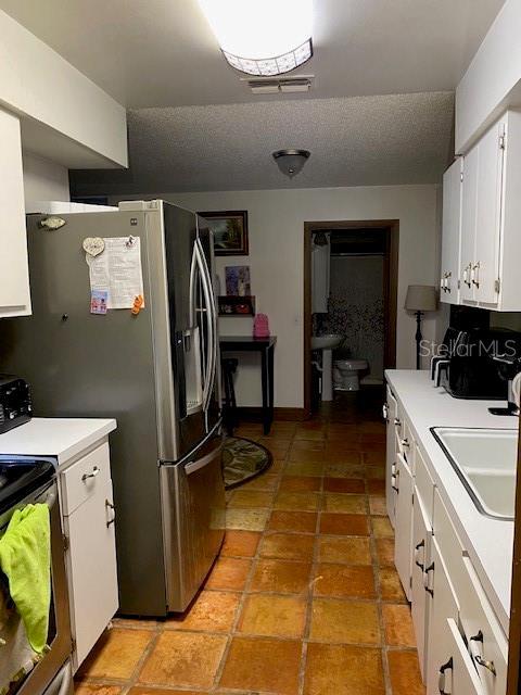 709 N Disston, Tavares, FL 32778 - kitchen featuring a sink, white cabinetry, light countertops, stainless steel appliances, and a textured ceiling