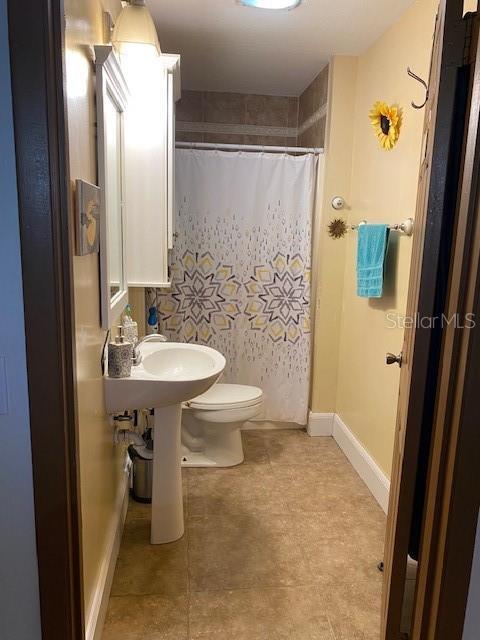 709 N Disston, Tavares, FL 32778 - bathroom featuring toilet, a shower with shower curtain, a sink, and baseboards