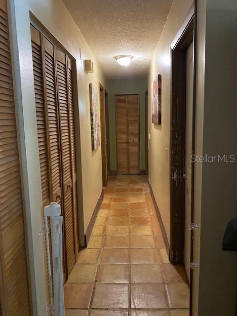 hallway featuring light tile patterned floors and a textured ceiling