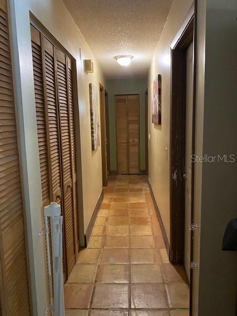 709 N Disston, Tavares, FL 32778 - corridor with a textured ceiling, light tile patterned flooring, and baseboards
