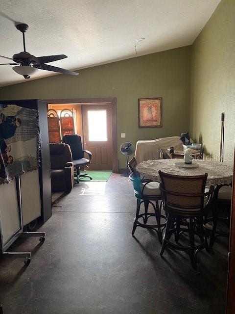 dining room featuring ceiling fan, concrete flooring, a textured ceiling, and lofted ceiling