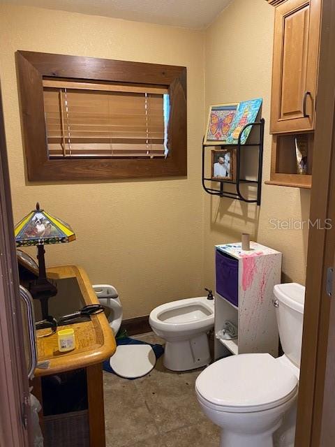 bathroom with tile patterned flooring, toilet, and a bidet