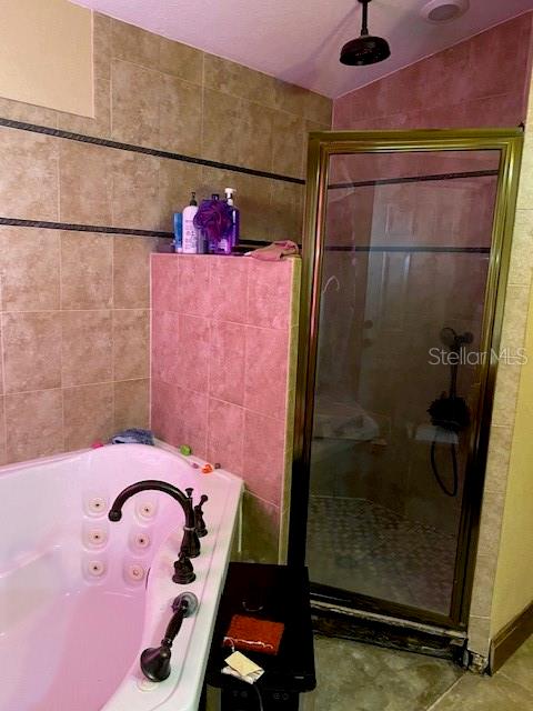 bathroom featuring tile patterned flooring, tile walls, vaulted ceiling, and a shower with shower door