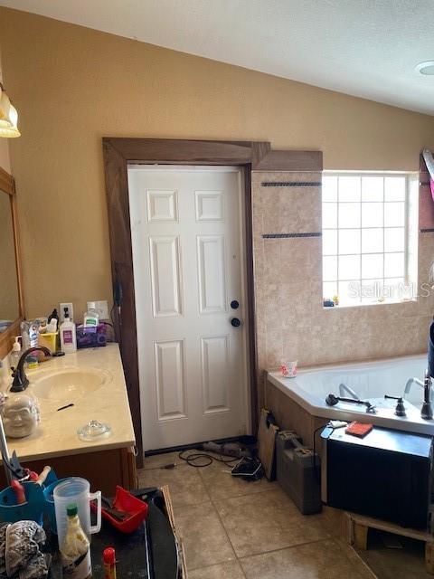 709 N Disston, Tavares, FL 32778 - full bath featuring a garden tub, lofted ceiling, vanity, and tile patterned flooring