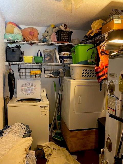 washroom with a textured ceiling, water heater, and separate washer and dryer