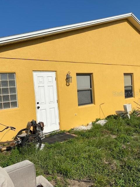 709 N Disston, Tavares, FL 32778 - doorway to property with stucco siding and a yard
