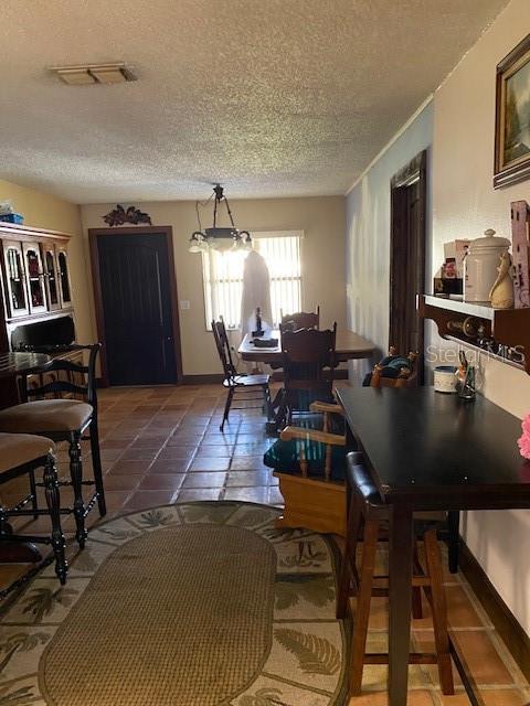 709 N Disston, Tavares, FL 32778 - dining area featuring a textured ceiling, tile patterned floors, and baseboards