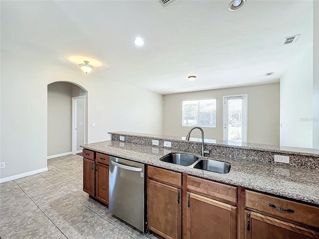 kitchen featuring stainless steel dishwasher, light stone countertops, and sink