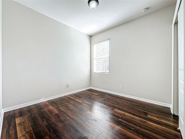 empty room featuring a textured ceiling and dark hardwood / wood-style floors