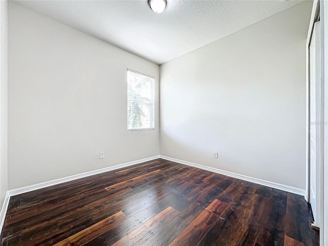 spare room featuring a textured ceiling and dark wood-type flooring