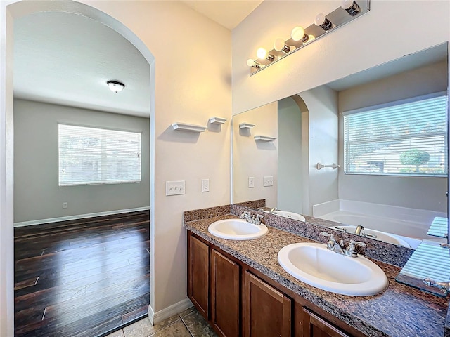 bathroom with a tub, vanity, and wood-type flooring