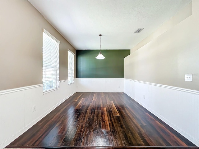 unfurnished dining area with dark hardwood / wood-style floors and a textured ceiling