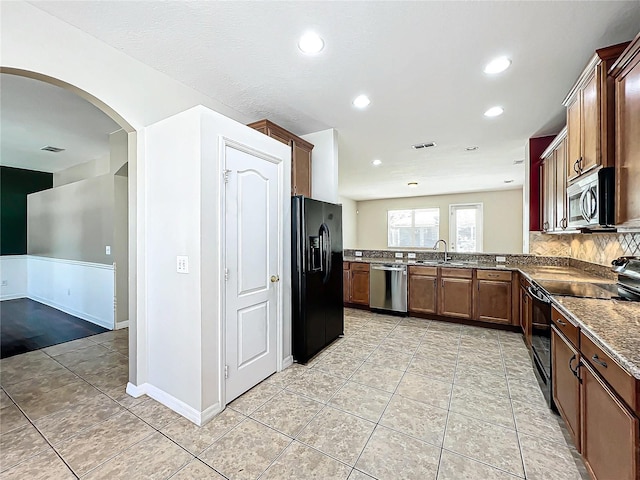 kitchen with backsplash, black appliances, sink, dark stone countertops, and light tile patterned flooring