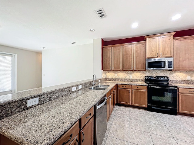 kitchen featuring decorative backsplash, light stone counters, stainless steel appliances, sink, and light tile patterned floors