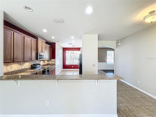 kitchen featuring a kitchen breakfast bar, a wealth of natural light, and appliances with stainless steel finishes