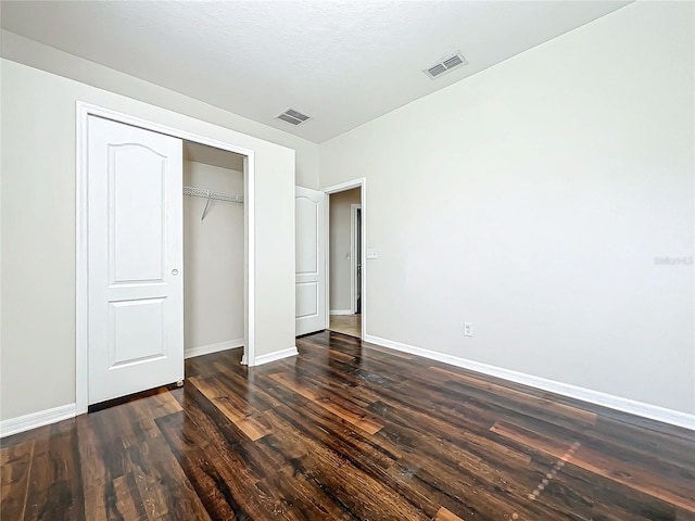 unfurnished bedroom featuring a textured ceiling, dark wood-type flooring, and a closet