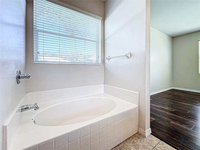 bathroom featuring wood-type flooring and tiled bath