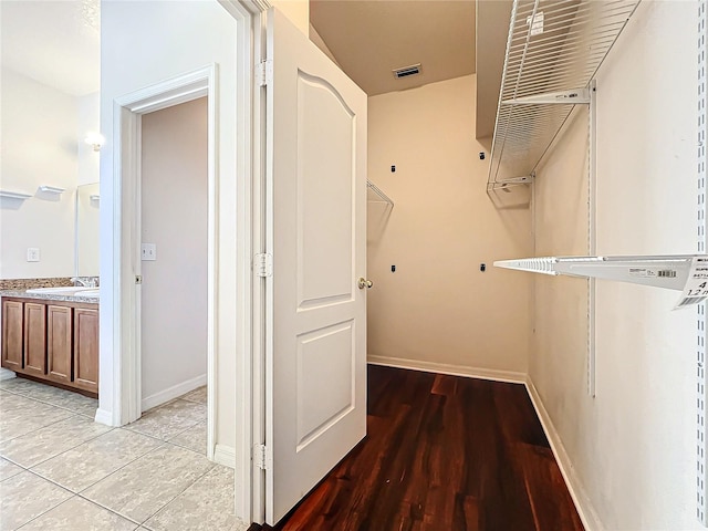 spacious closet with light hardwood / wood-style floors and sink