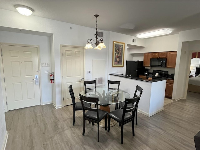 dining space with light wood-type flooring, visible vents, and a notable chandelier