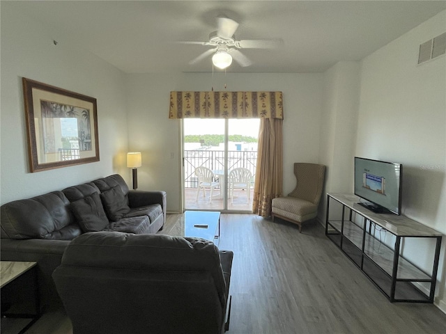 living room with light wood-type flooring, visible vents, and ceiling fan