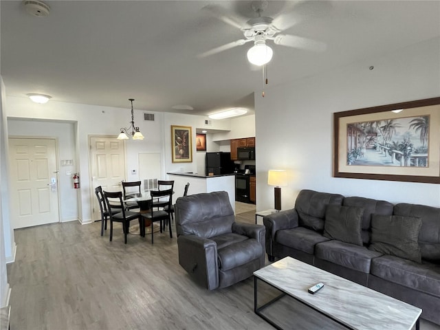 living area featuring light wood-style floors, visible vents, and a ceiling fan