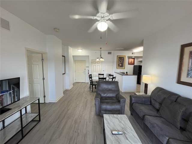 living area with baseboards, ceiling fan, visible vents, and wood finished floors