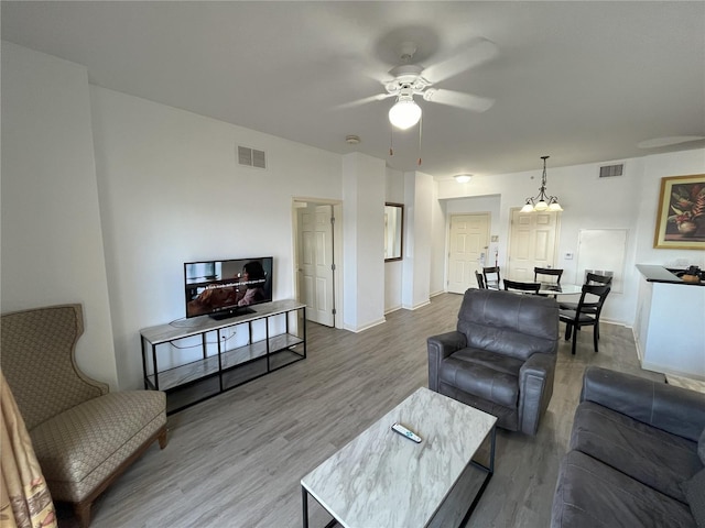 living room with a ceiling fan, visible vents, and wood finished floors