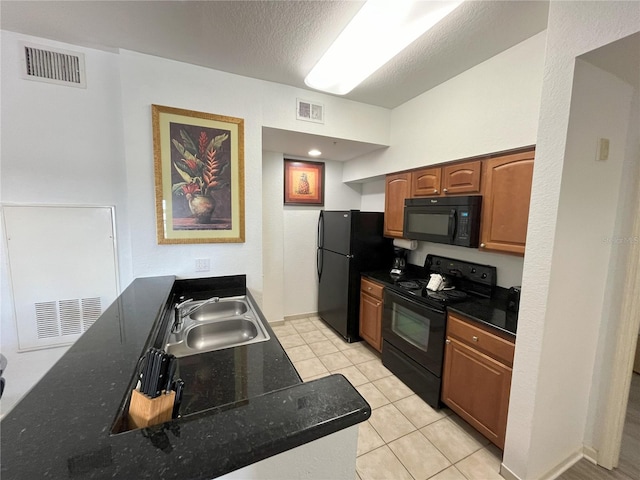 kitchen featuring brown cabinetry, visible vents, a sink, and black appliances