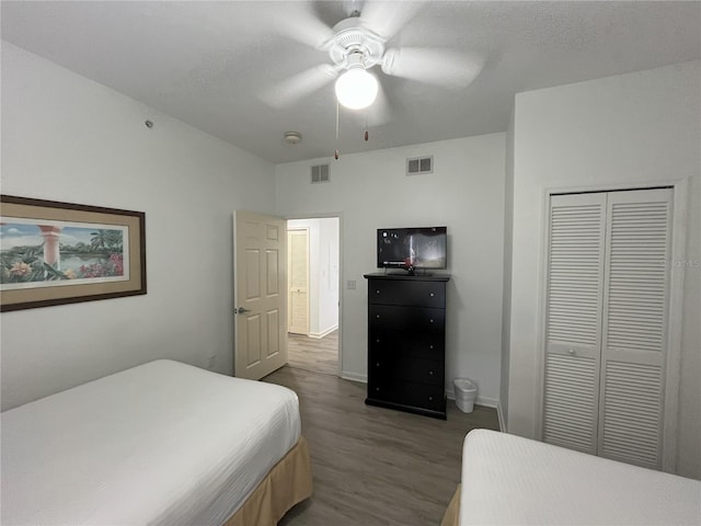 bedroom with a textured ceiling, dark wood-type flooring, a closet, and visible vents