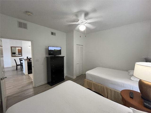 bedroom featuring a closet, visible vents, baseboards, and wood finished floors