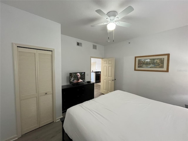 bedroom with ceiling fan, visible vents, a closet, and wood finished floors