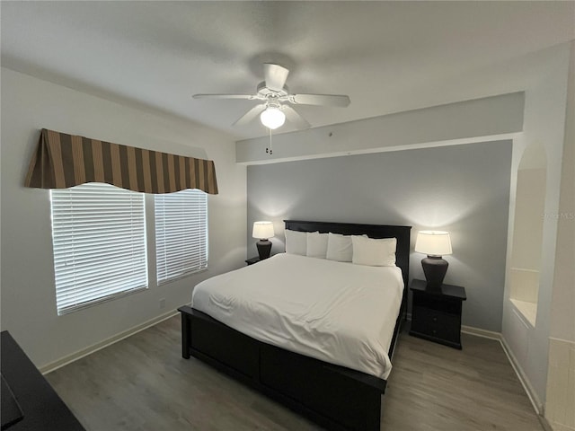 bedroom featuring ceiling fan, baseboards, and wood finished floors