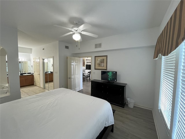 bedroom featuring light wood-type flooring, visible vents, connected bathroom, and ceiling fan