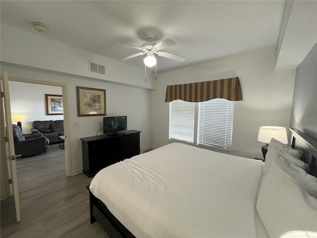 bedroom featuring a ceiling fan, visible vents, and wood finished floors