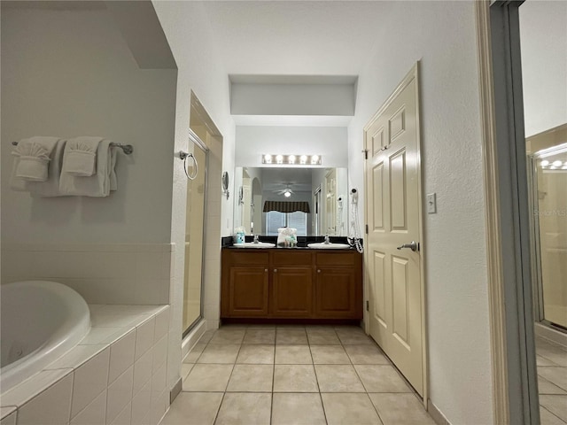 bathroom with double vanity, tiled bath, tile patterned flooring, and a shower stall