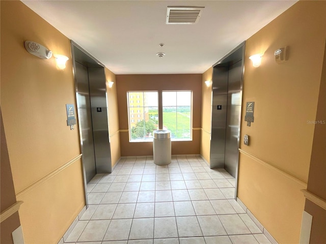 corridor with elevator, light tile patterned floors, and visible vents