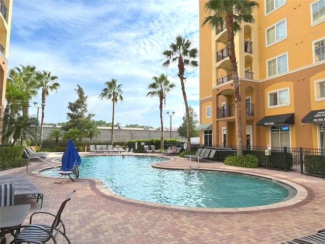 community pool with a patio area and fence