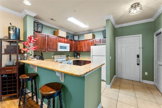 kitchen featuring light stone counters, kitchen peninsula, white appliances, and ornamental molding