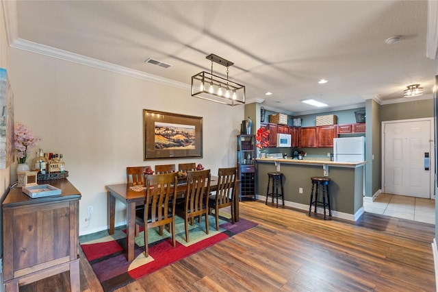 dining space featuring ornamental molding and light wood-type flooring