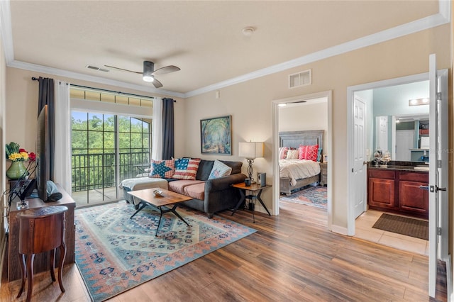 living room with light hardwood / wood-style floors, crown molding, and ceiling fan