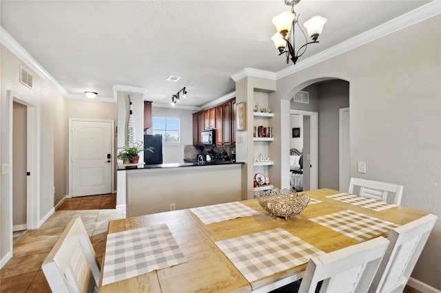 dining space featuring crown molding, a chandelier, track lighting, and light tile patterned floors