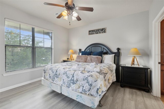 bedroom featuring a ceiling fan, baseboards, visible vents, and light wood finished floors