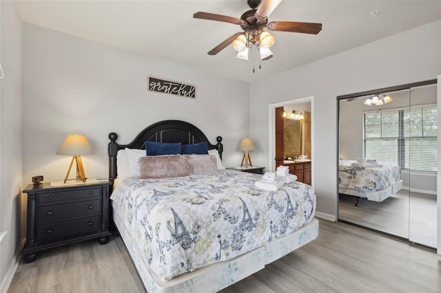 bedroom featuring ensuite bath, light hardwood / wood-style flooring, ceiling fan with notable chandelier, and a closet