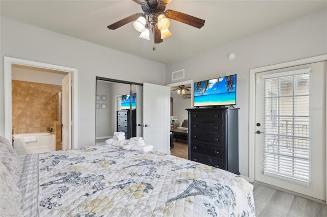 bedroom featuring hardwood / wood-style flooring, multiple windows, ensuite bath, and ceiling fan