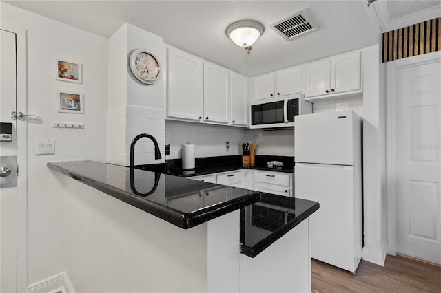 kitchen featuring light hardwood / wood-style flooring, white refrigerator, sink, kitchen peninsula, and white cabinetry