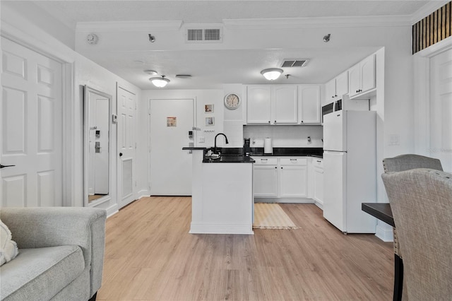 kitchen featuring sink, backsplash, light wood-type flooring, white cabinetry, and white fridge