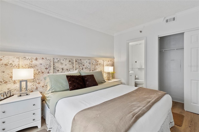 bedroom featuring ensuite bath, ornamental molding, a closet, and light hardwood / wood-style floors