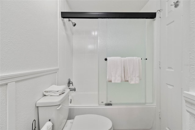 bathroom featuring toilet and shower / bath combination with glass door